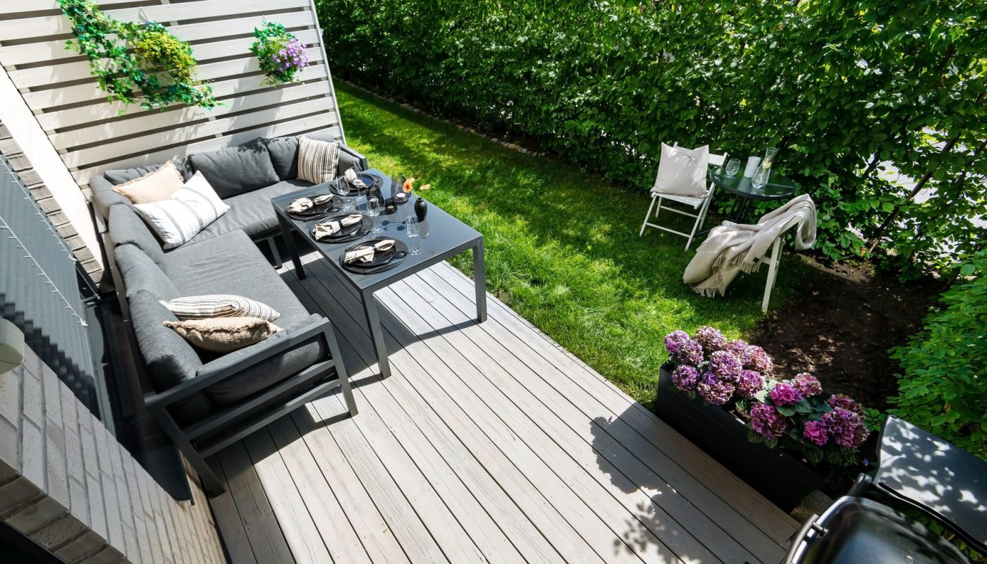 Holzterrasse mit Loungemöbeln und Hortensien am Rasen