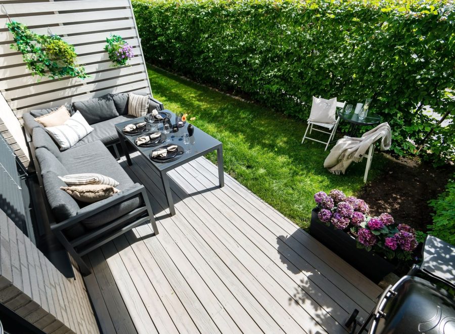 Holzterrasse mit Loungemöbeln und Hortensien am Rasen