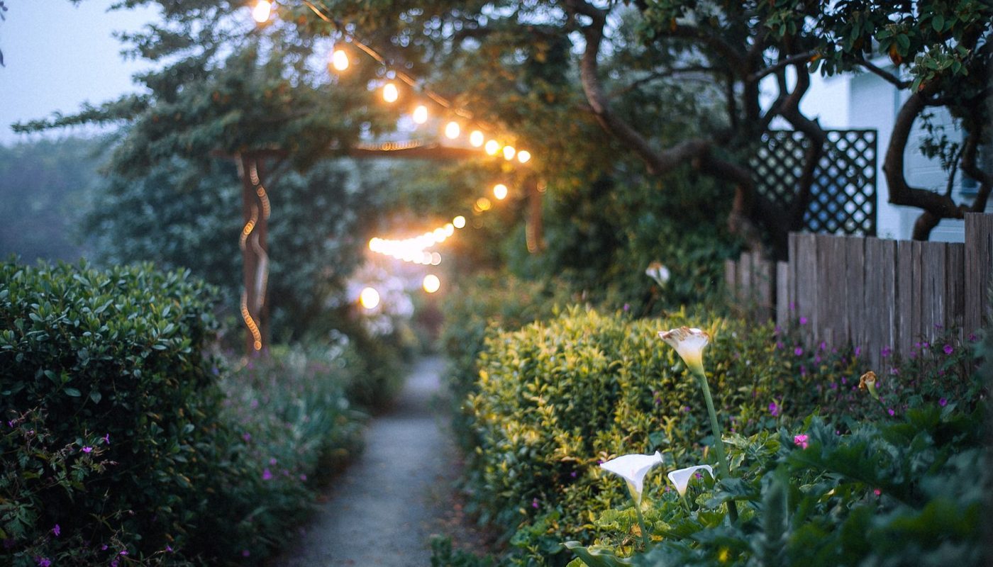 Gartenweg mit warmer Lichterkette in der Dämmerung