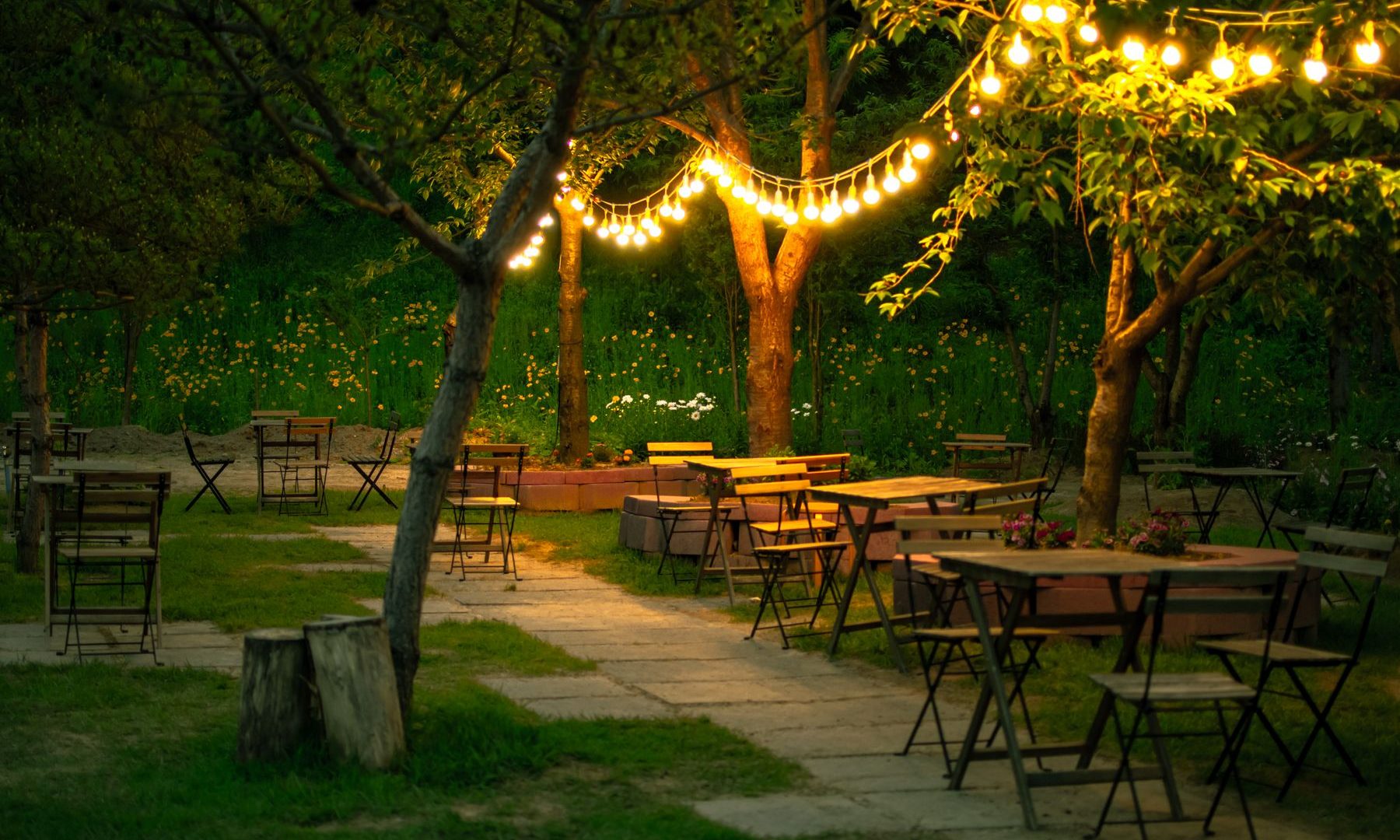 Abendlich beleuchteter Garten mit Lichterketten und Sitzplätzen